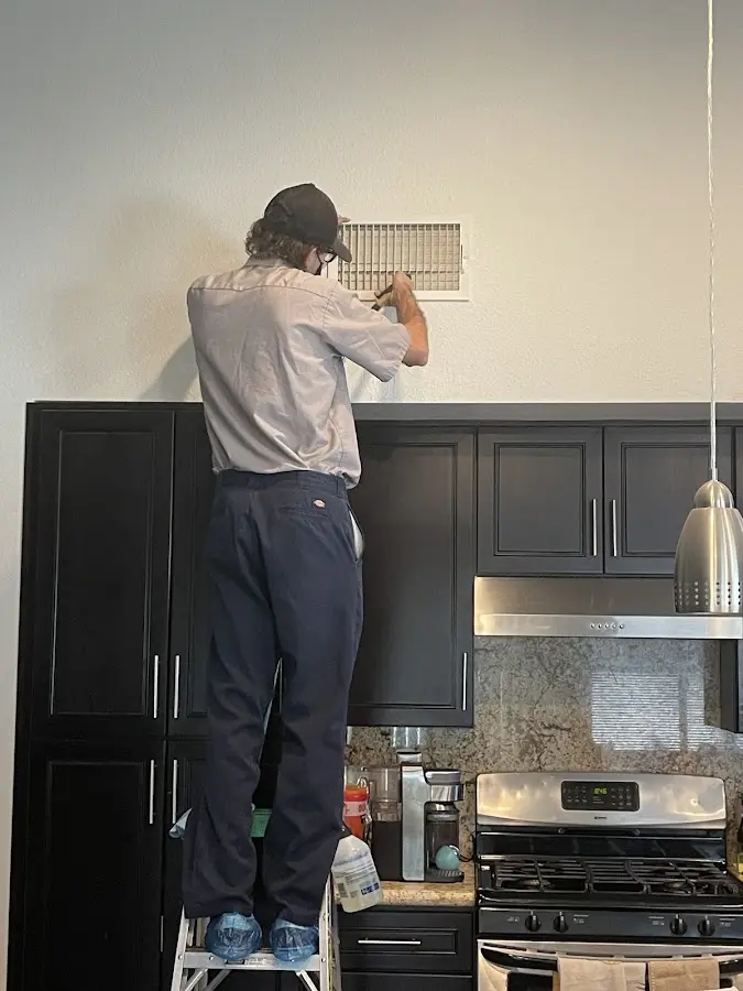 Technician inspecting an air vent during HVAC service in West Hartford